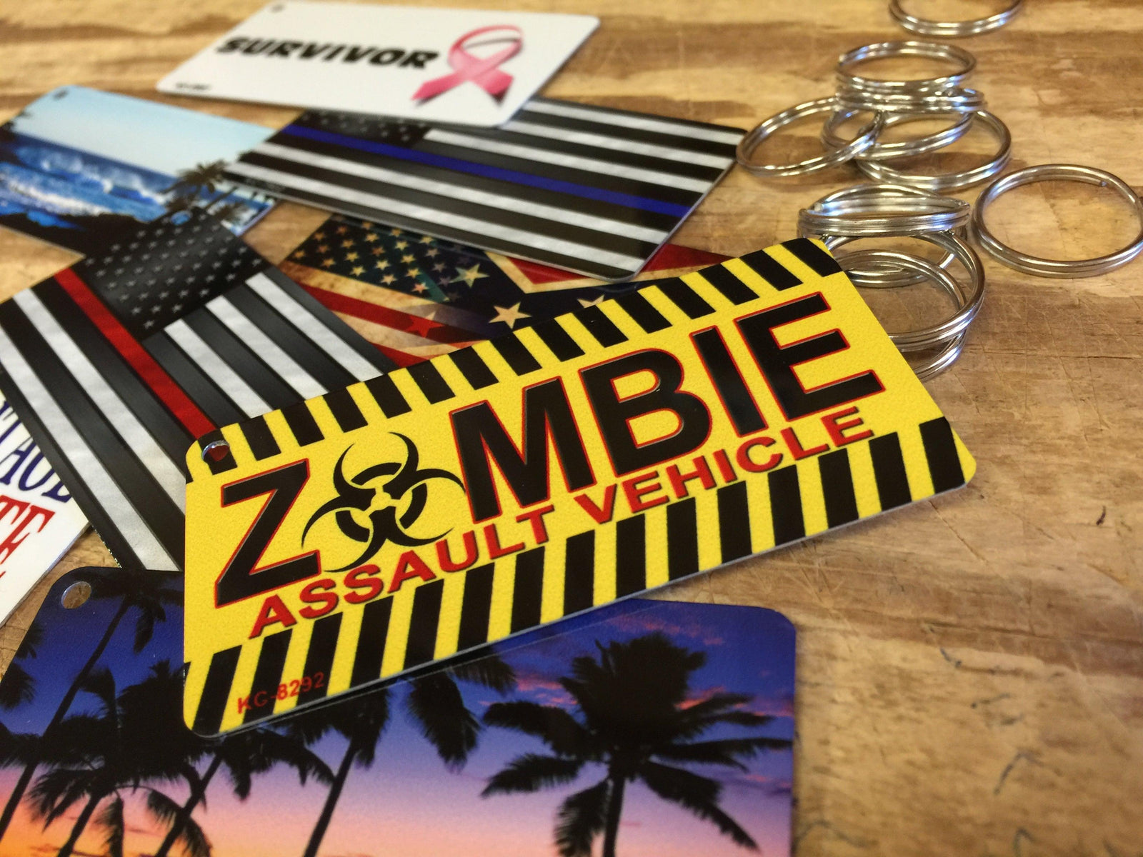 Novelty keychains with custom designs including zombie assault vehicle and flags on wood