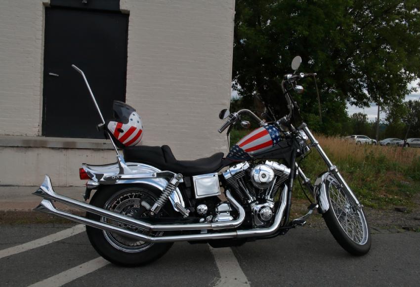 Custom chrome motorcycle with American flag tank and helmet parked on city street