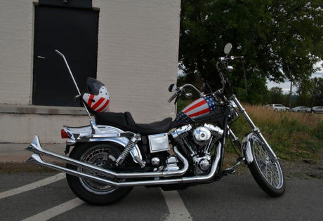 Custom chrome motorcycle with American flag tank and helmet parked on city street