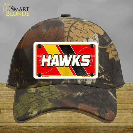 Camouflage cap with a 'HAWKS' license plate design on a wooden surface.