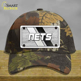 Camouflage cap with a 'NETS' logo on a wooden surface