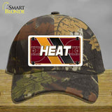 Camouflage cap with a 'HEAT' license plate design on a wooden surface.