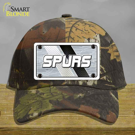Camouflage cap with a 'SPURS' license plate design on a wooden surface.