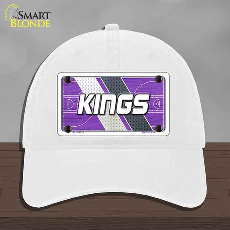 White cap with a purple and gray 'KINGS' design on a wooden surface.