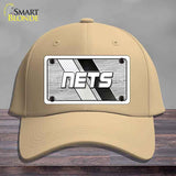 Beige cap with 'NETS' logo on a wooden surface and gray background